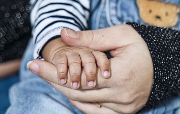 mains d'un bébé et de sa maman entrelacées